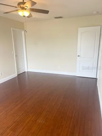 a view of an empty room with wooden floor and windows