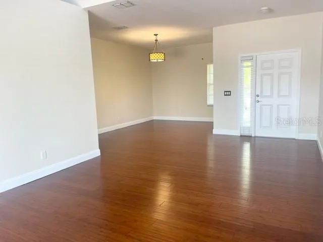 a view of an empty room with window and wooden floor