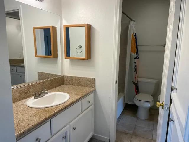 a bathroom with a granite countertop sink toilet and shower
