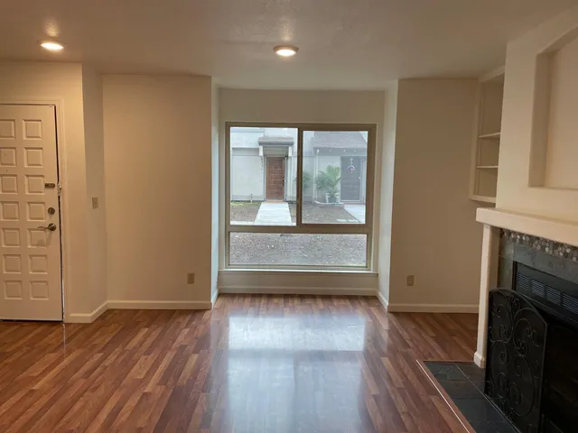an empty room with wooden floor and a fireplace