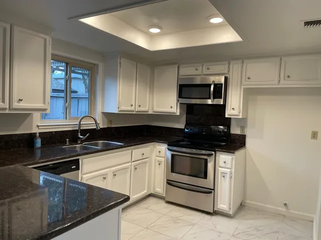 a kitchen with granite countertop a stove sink and cabinets