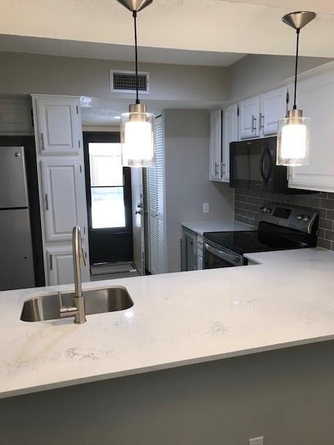 18240 Midway Road, Unit 303 Dallas, TX 75287 - Photo 3 of 22 Kitchen with stainless steel appliances, white cabinetry, tasteful backsplash, a peninsula, and pendant lighting