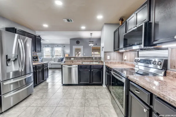 a kitchen with stainless steel appliances granite countertop a stove top oven a sink and a refrigerator