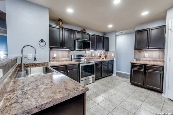 a large kitchen with stainless steel appliances kitchen island granite countertop a stove and a sink