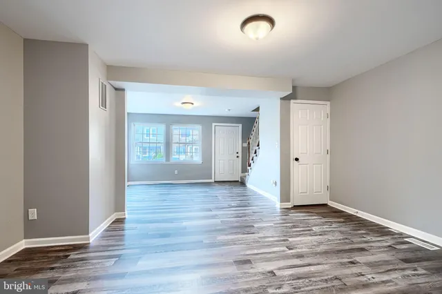 a view of an empty room with window and wooden floor