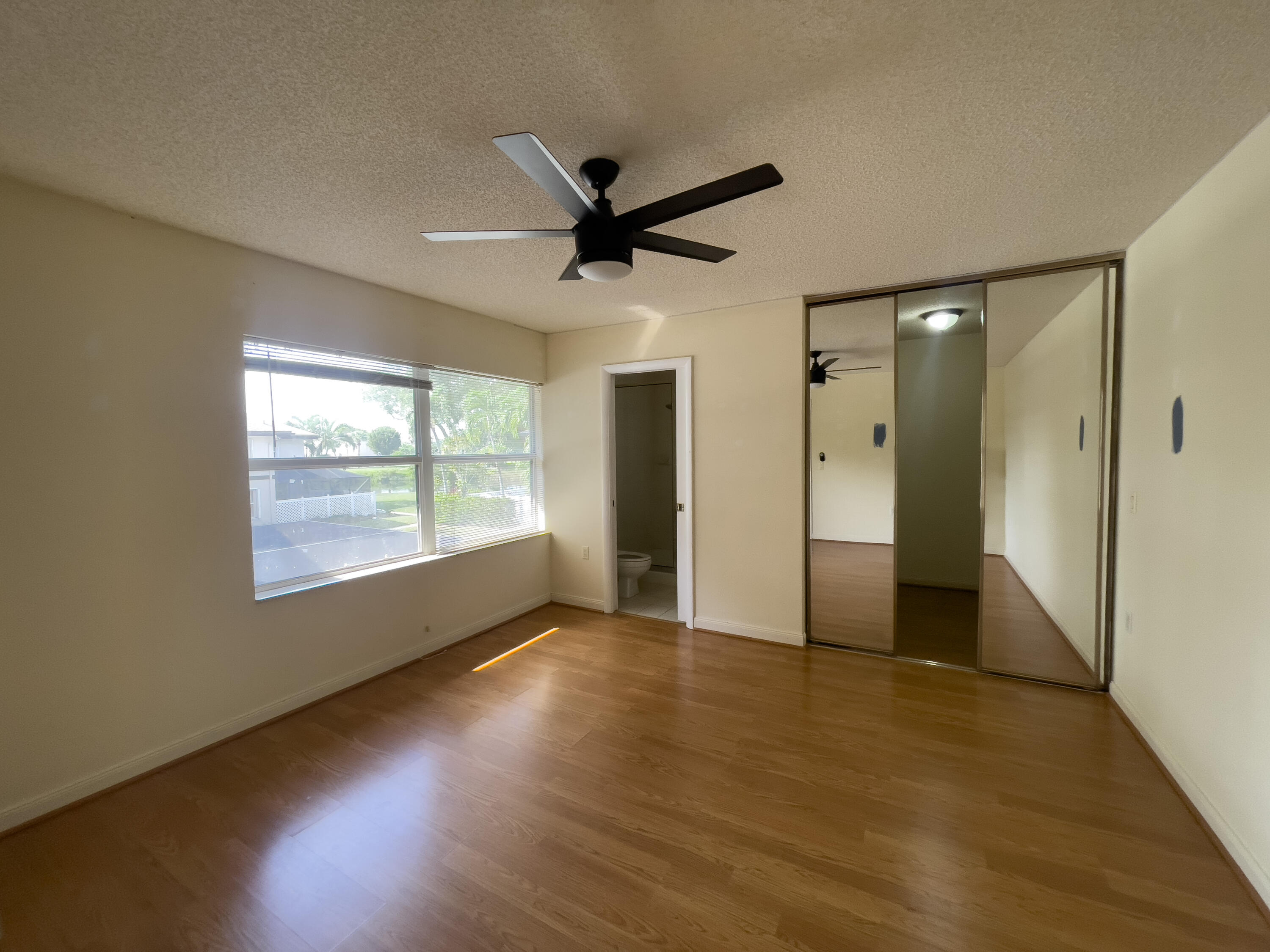 27 Clinton Court, Unit D Royal Palm Beach, FL 33411 - Photo 26 of 32 an empty room with wooden floor and windows