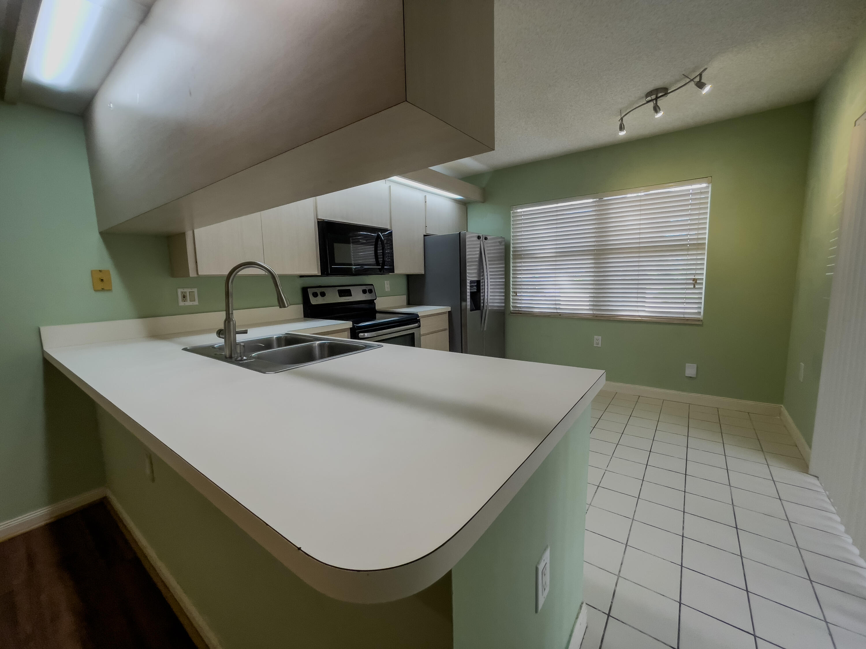27 Clinton Court, Unit D Royal Palm Beach, FL 33411 - Photo 6 of 32 a kitchen with kitchen island a sink a stove top oven a chimney and a window