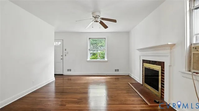 an empty room with wooden floor fireplace and windows