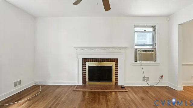 a view of an empty room with wooden floor and a fireplace