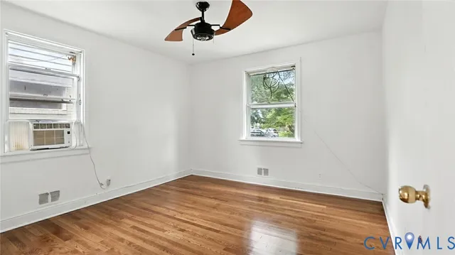 a view of empty room with wooden floor and fan