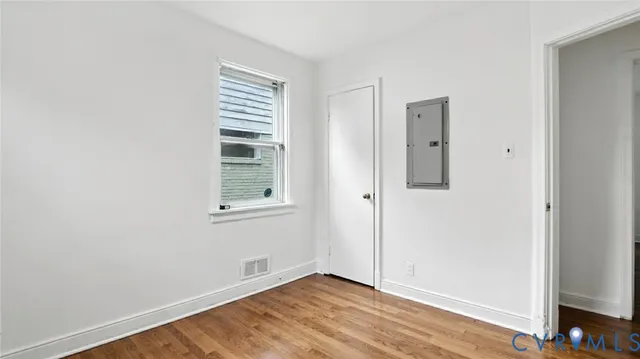 an empty room with wooden floor and windows