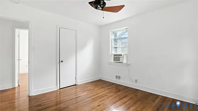an empty room with wooden floor cabinet and windows
