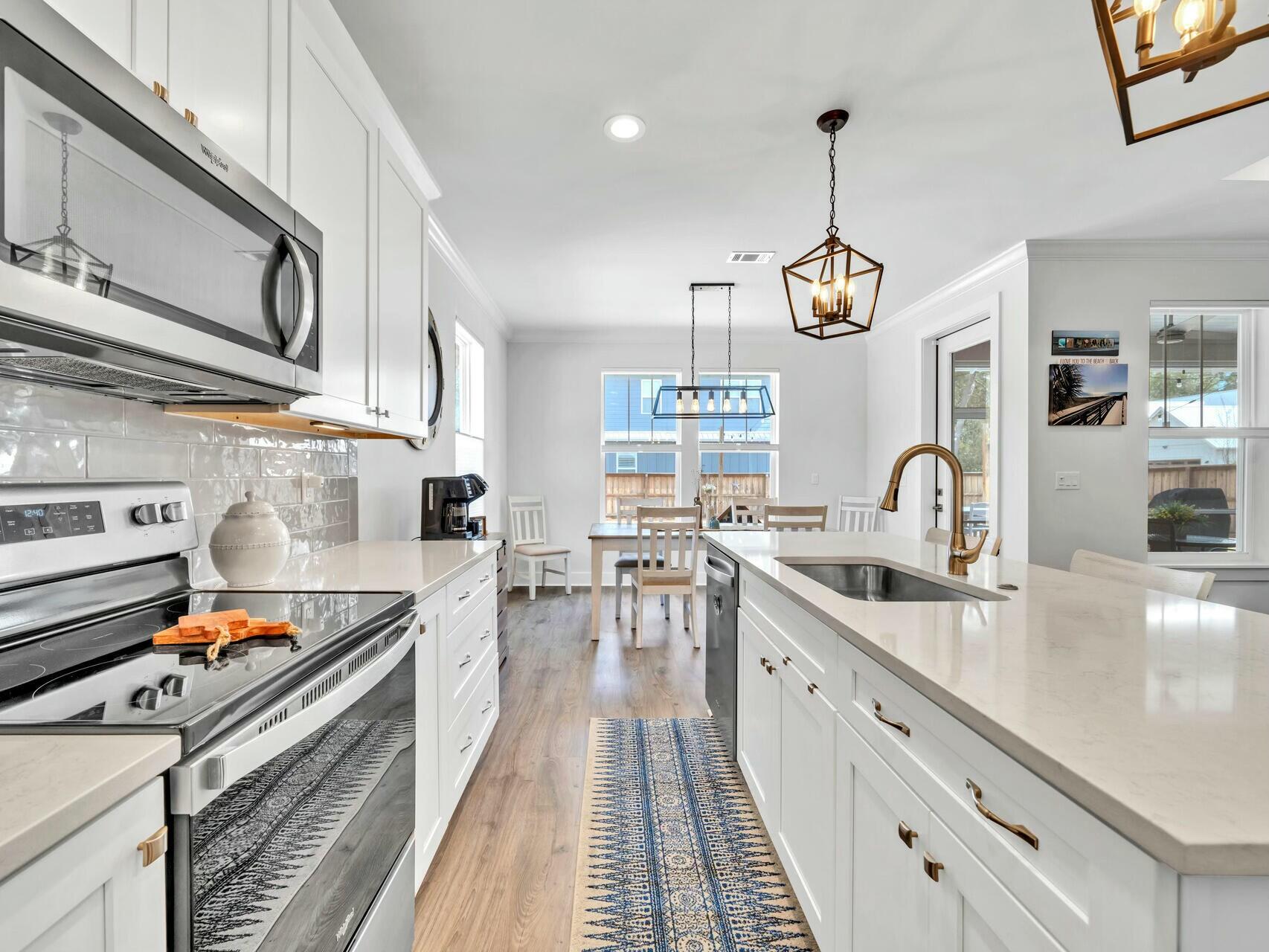 176 Hibernate Way Freeport, FL 32439 - Photo 20 of 66 a kitchen with stainless steel appliances granite countertop a stove a sink dishwasher and white cabinets with wooden floor
