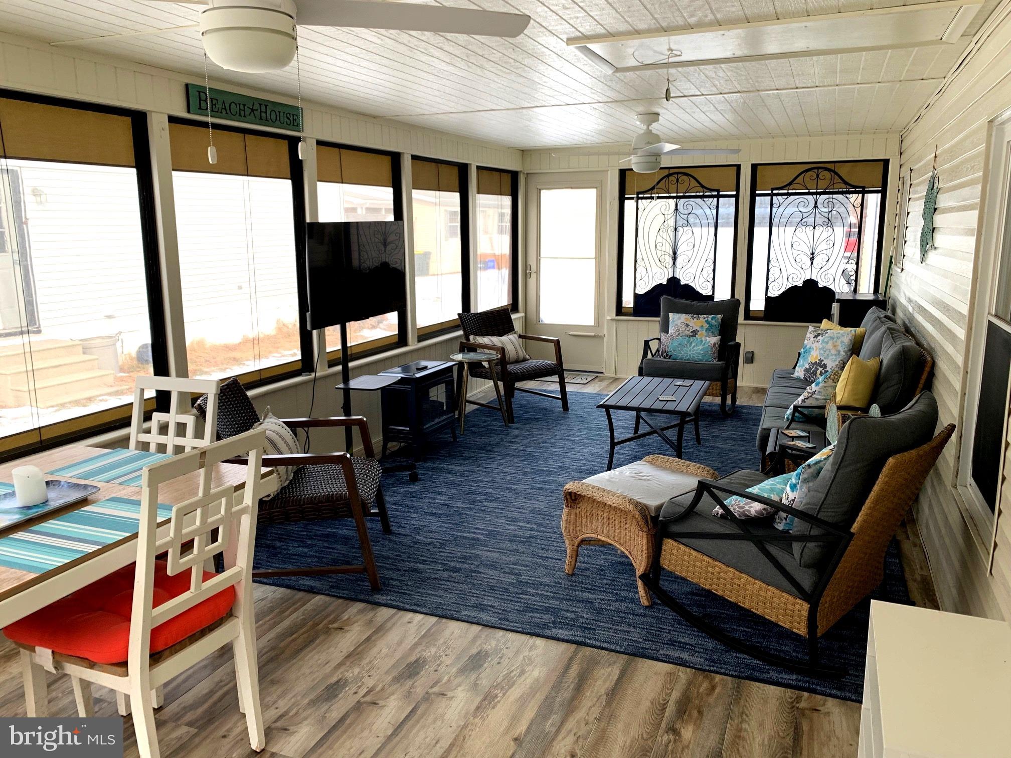 21229 M Street Rehoboth Beach, DE 19971 - Photo 5 of 23 a living room with furniture a flat screen tv and large windows