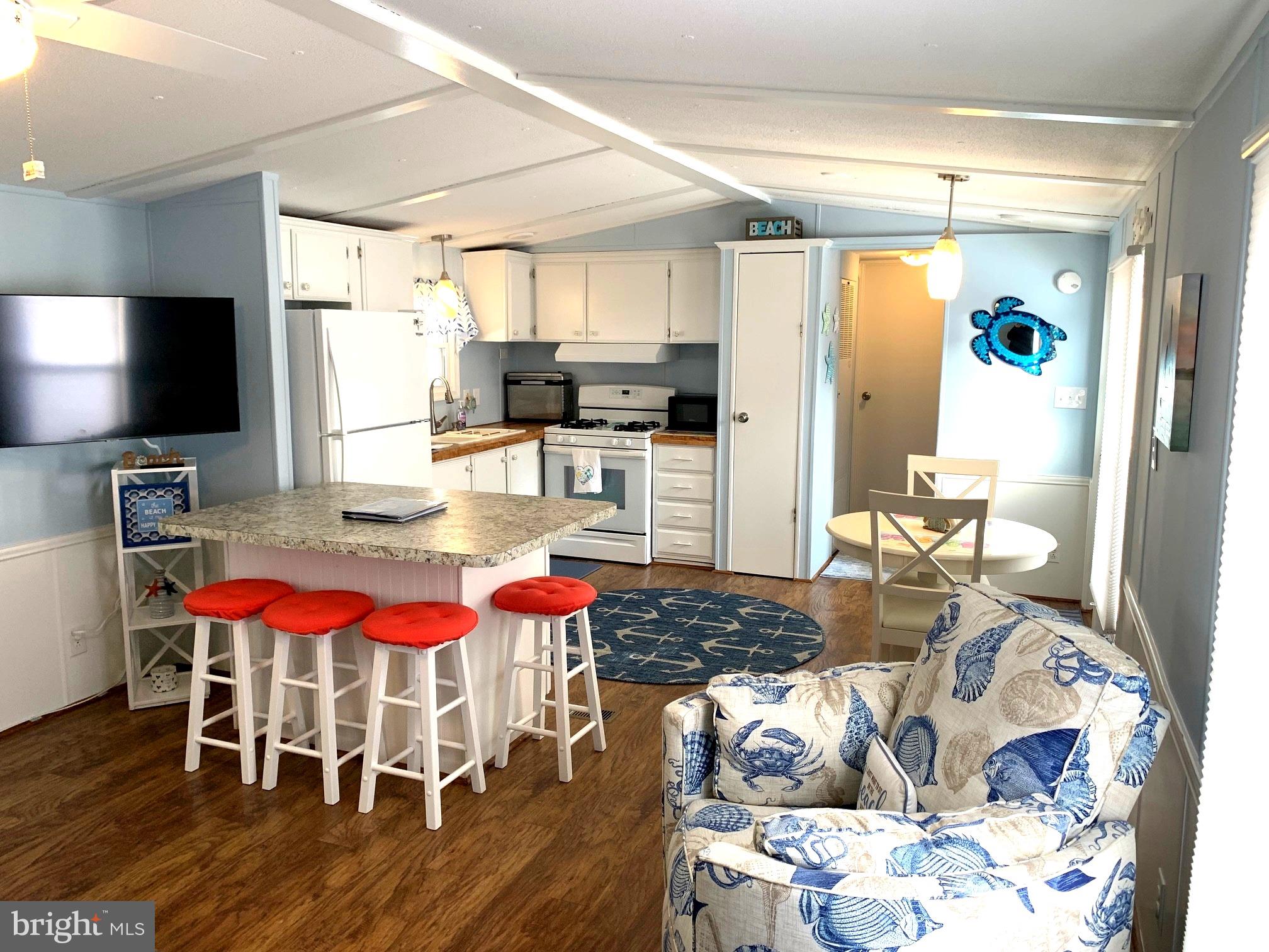 21229 M Street Rehoboth Beach, DE 19971 - Photo 8 of 23 a kitchen with stainless steel appliances granite countertop a stove top oven a dining table and chairs