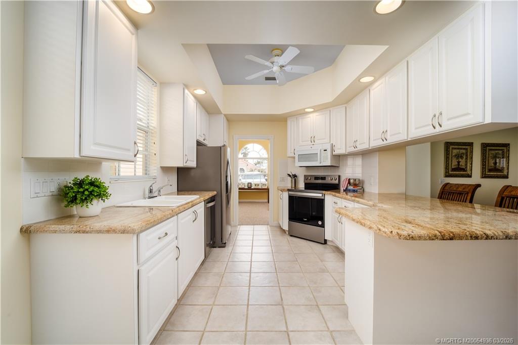 1477 Southwest Eagleglen Place Stuart, FL 34997 - Photo 9 of 36 a kitchen with kitchen island granite countertop a sink counter top space appliances and cabinets
