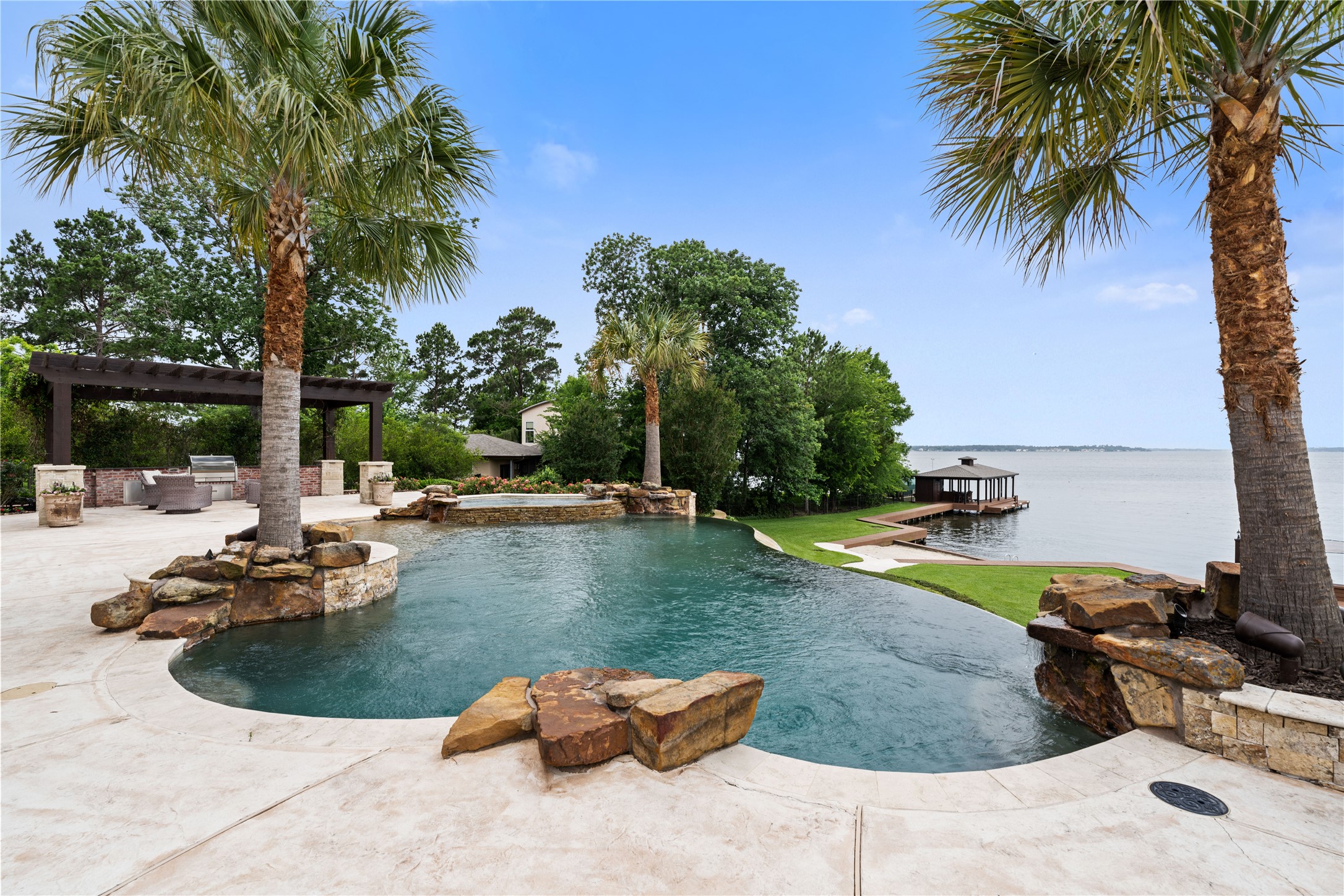 12349 Longmire Trace Conroe, TX 77304 - Photo 38 of 48 Resort-style infinity-edge pool overlooks the lake, with stone water features and private boat dock.