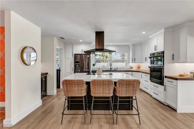 a kitchen with stainless steel appliances a dining table chairs and wooden floor