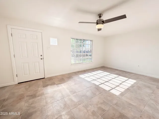 an empty room with windows and ceiling fan view