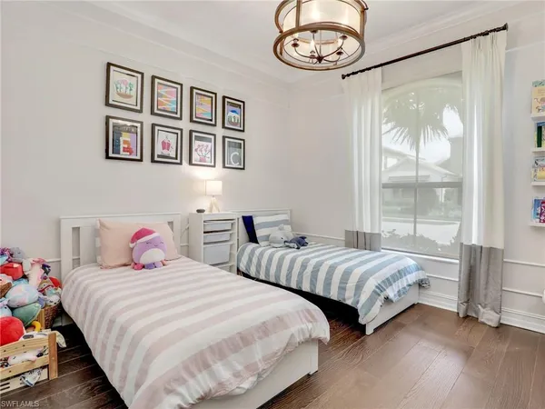 a bedroom with two beds and a large mirror next to a window