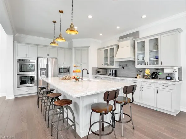 a kitchen with stainless steel appliances a dining table chairs stove refrigerator and cabinets
