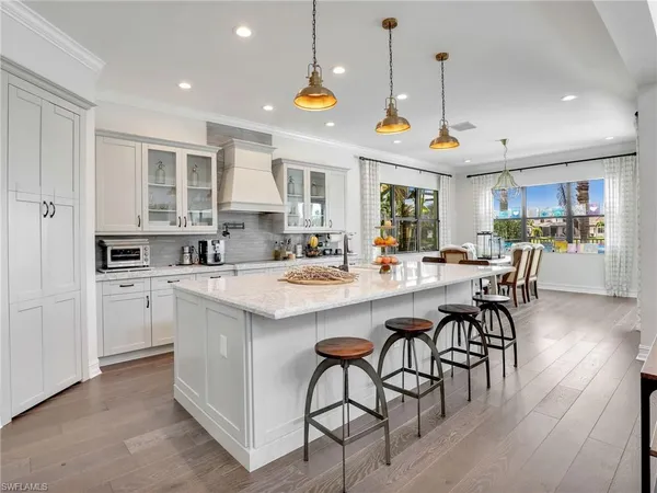 a kitchen with stainless steel appliances kitchen island granite countertop a stove a sink a refrigerator and white cabinets with wooden floor