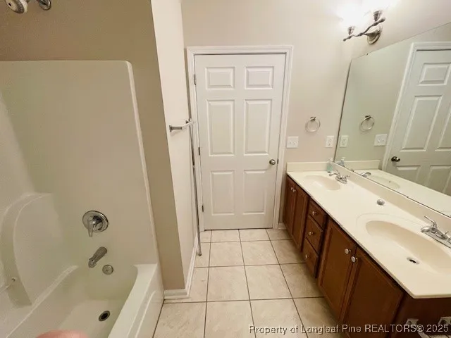 a bathroom with a double vanity sink a mirror and a bathtub