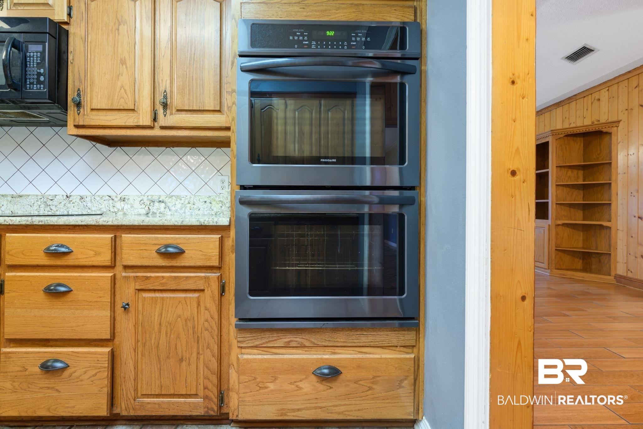 7540 2 Mile Road Irvington, AL 36544 - Photo 47 of 82 Kitchen featuring light wood cabinetry with dark hardware, a stacked double wall oven, and a white diagonal tile backsplash