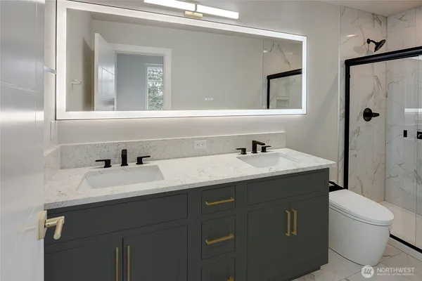 a bathroom with a granite countertop sink toilet a mirror and shower
