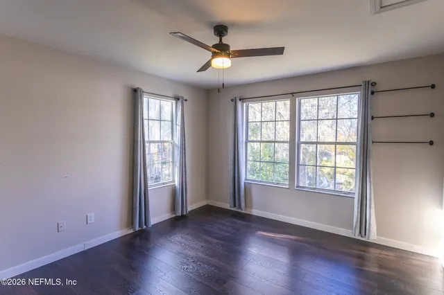 a view of an empty room with window and wooden floor