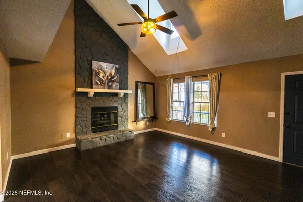a view of an empty room with window and wooden floor