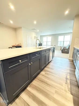 a large kitchen with stainless steel appliances granite countertop a sink dishwasher a stove and white countertops with wooden floor