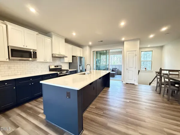 a large kitchen with stainless steel appliances and white cabinets