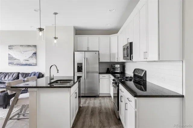 a kitchen with stainless steel appliances a sink a stove a refrigerator and cabinets
