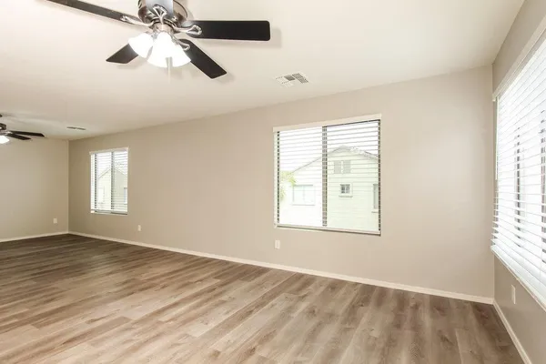 a view of an empty room with a window and wooden floor