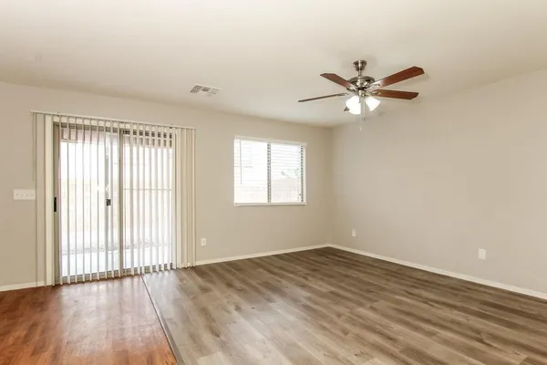 an empty room with wooden floor fan and windows