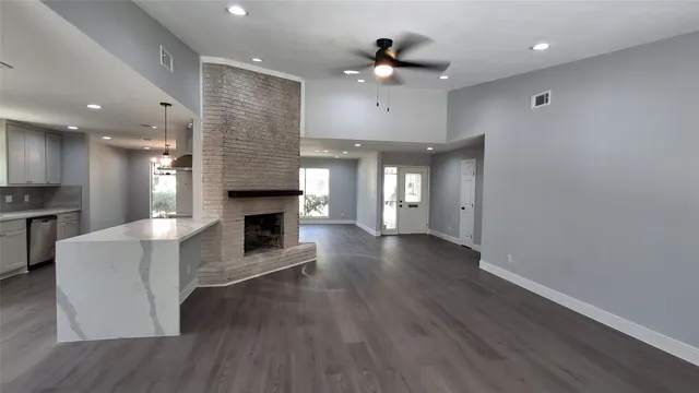 a view of a livingroom with a fireplace a chandelier and wooden floor