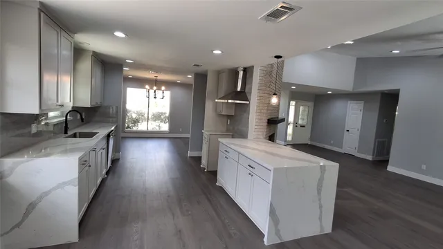 a large kitchen with stainless steel appliances kitchen island a large counter top a sink a stove and a refrigerator