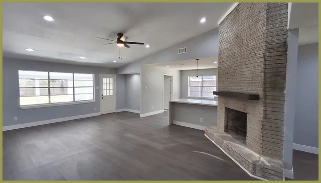 an open kitchen with fireplace and wooden floor