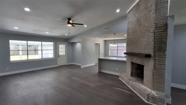an empty room with windows and fireplace
