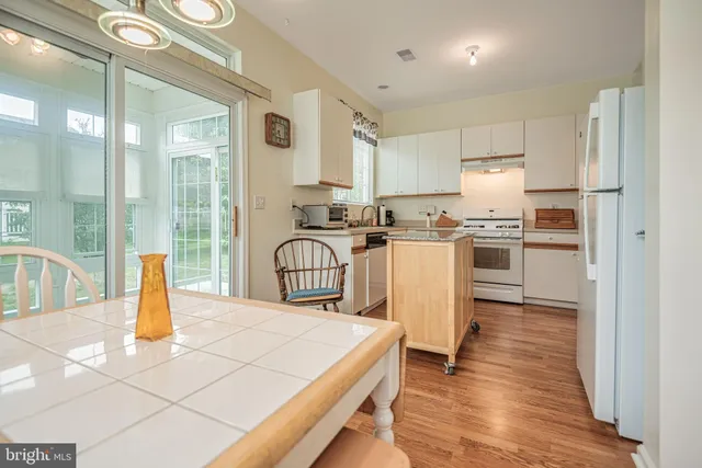 a kitchen with stainless steel appliances granite countertop a refrigerator a stove top oven and a view of living room