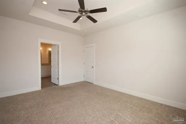 an empty room with a ceiling fan and carpet