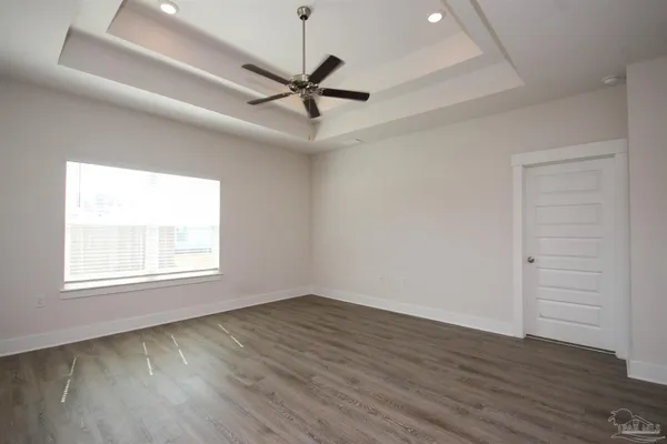 an empty room with wooden floor ceiling fan and windows