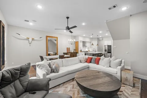 a living room with furniture kitchen view and a chandelier