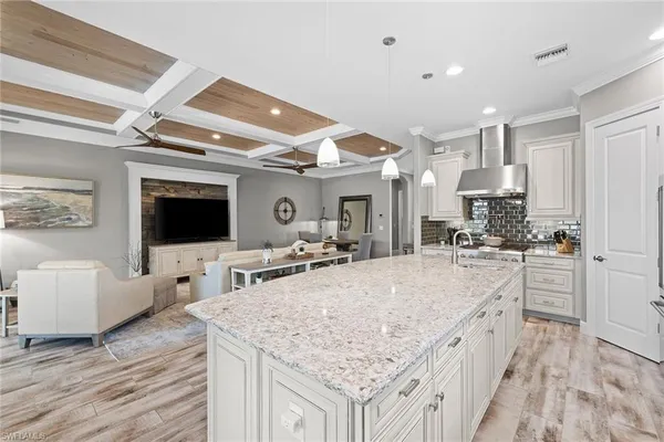 a large kitchen with kitchen island a flat screen tv and living room view