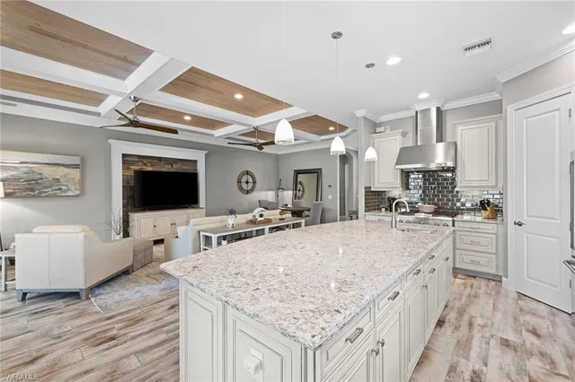 a large kitchen with kitchen island a flat screen tv and living room view