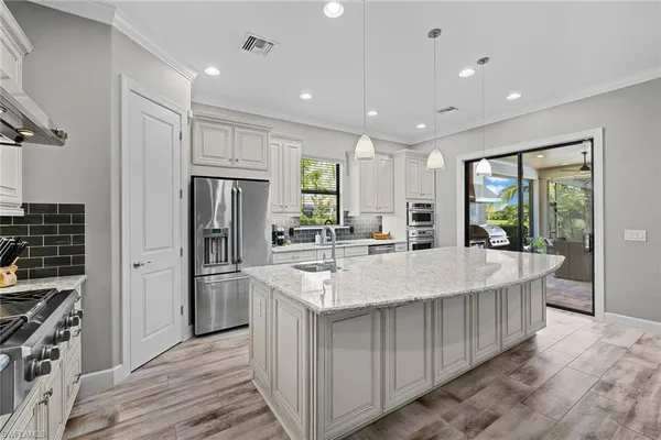 a large kitchen with stainless steel appliances granite countertop a large counter top a stove and a refrigerator