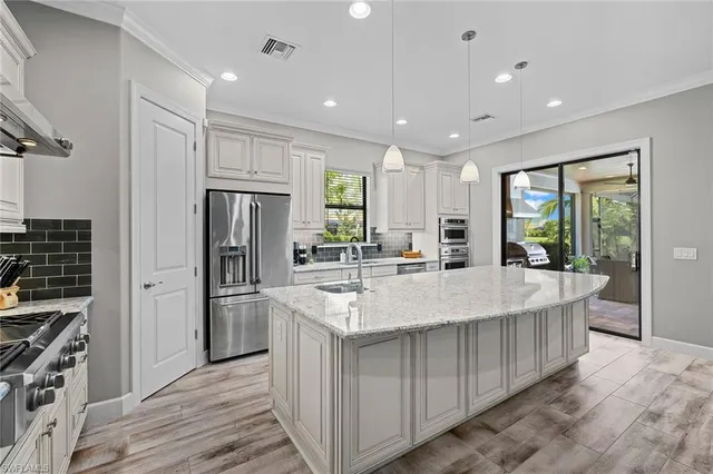 a large kitchen with stainless steel appliances granite countertop a large counter top a stove and a refrigerator