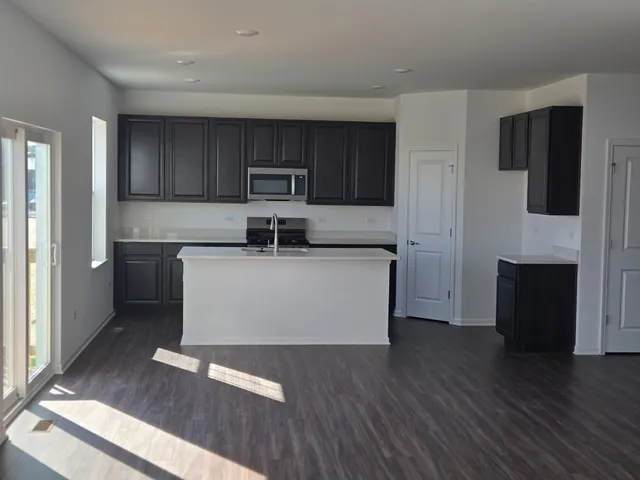 a view of kitchen with stainless steel appliances granite countertop a stove top oven a sink and a refrigerator