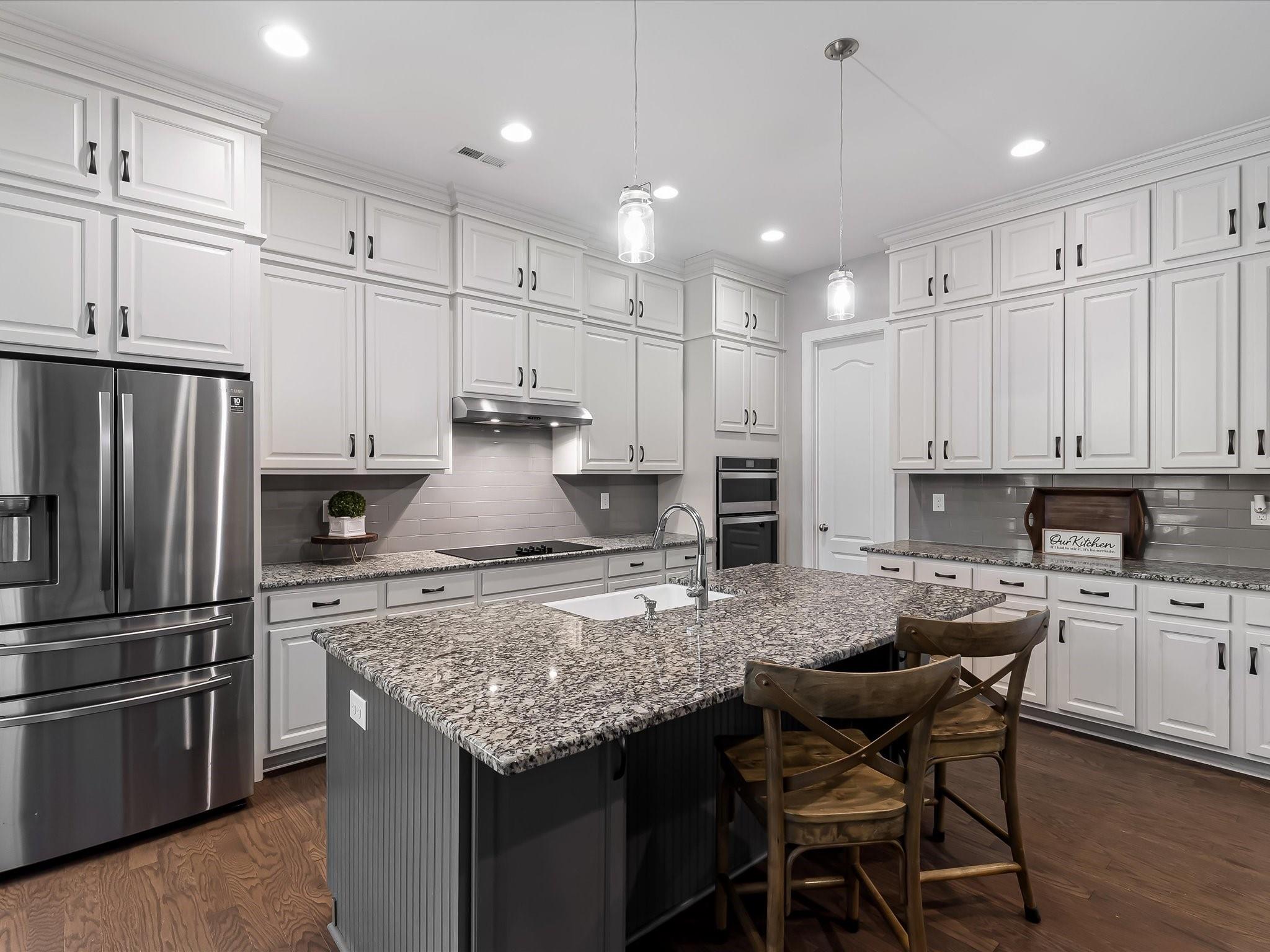 4876 Killian Crossing Drive Denver, NC 28037 - Photo 10 of 46 a kitchen with kitchen island granite countertop a table chairs microwave and refrigerator